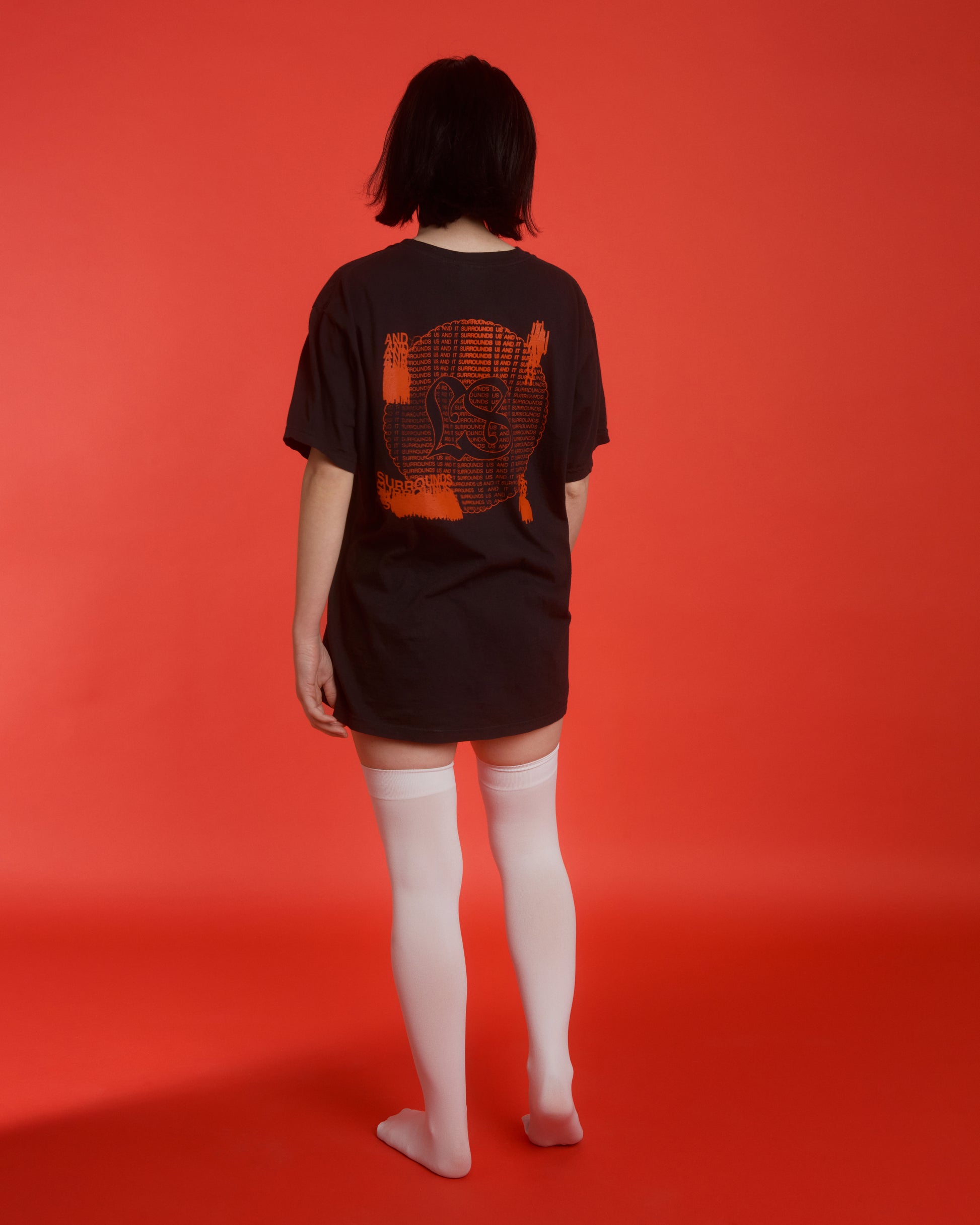 The backside of the "bathwater" black t-shirt with red text against a bright red background.